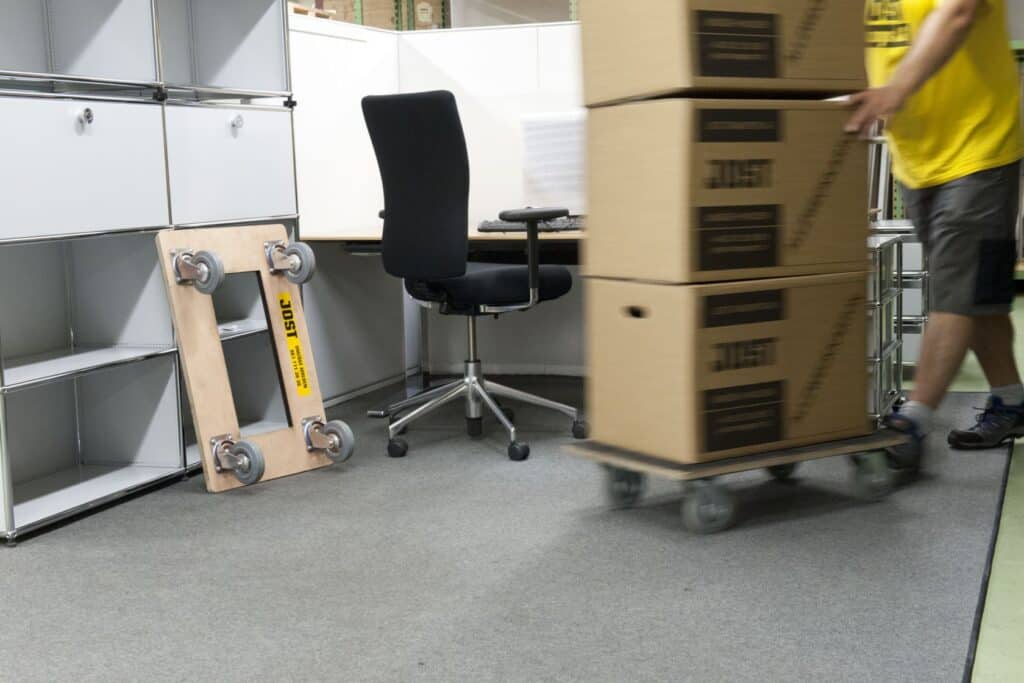 Movers transporting packed boxes on a dolly in an office moving service.