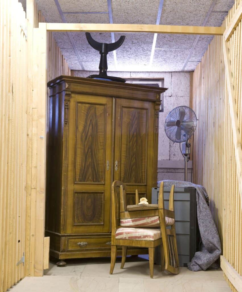 Handmade wooden furniture in storage room with rustic decor and wooden walls.