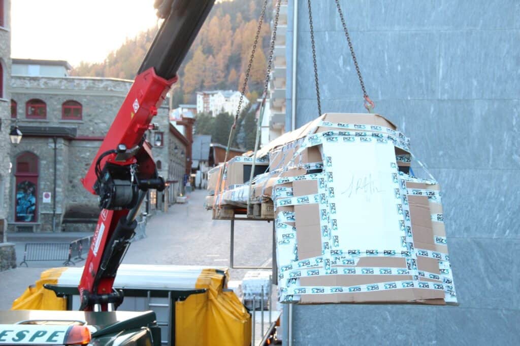 Crane lifting a package wrapped in protective tape during building construction or renovation.