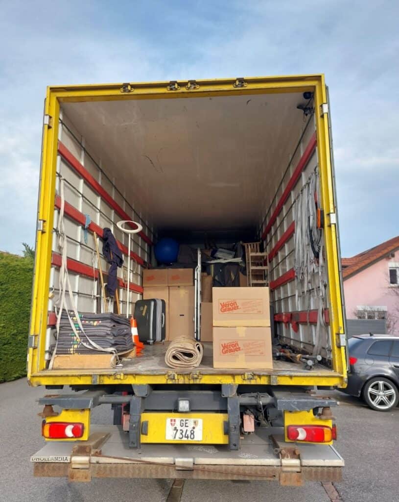 Light yellow moving truck with packed supplies and furniture, ready for relocation services.